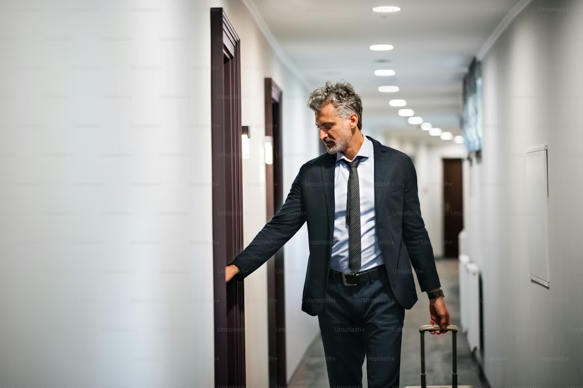 Businessman pulling a suitcase while walking through a hotel corridor, Intercity Chauffeur Routes