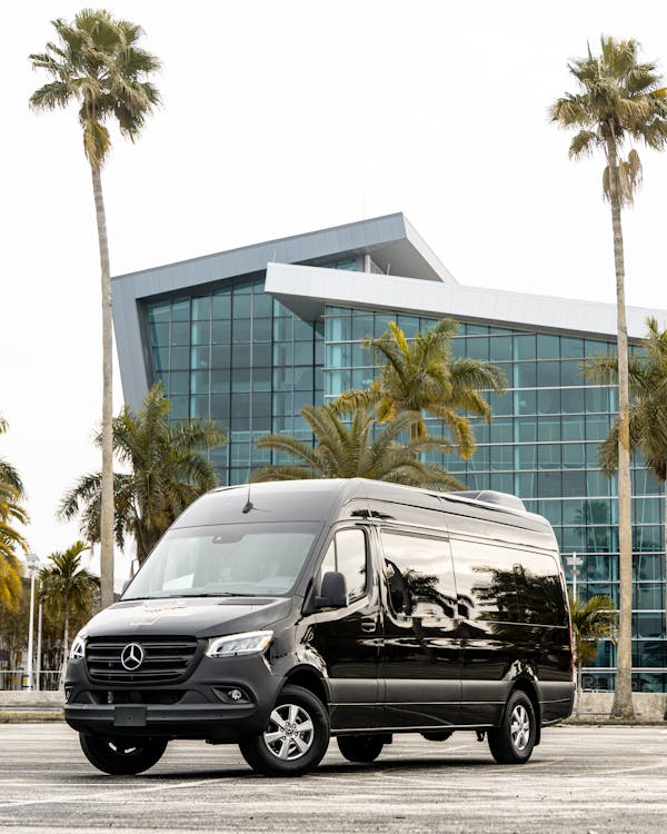 Black luxury van parked outside a corporate office building, representing premium chauffeur-driven executive transport for business clients.