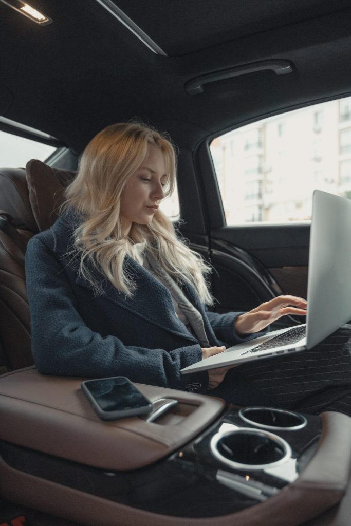 hourly cabs service - Woman working on laptop inside a cab, productive business commute, urban ride, remote office on the go