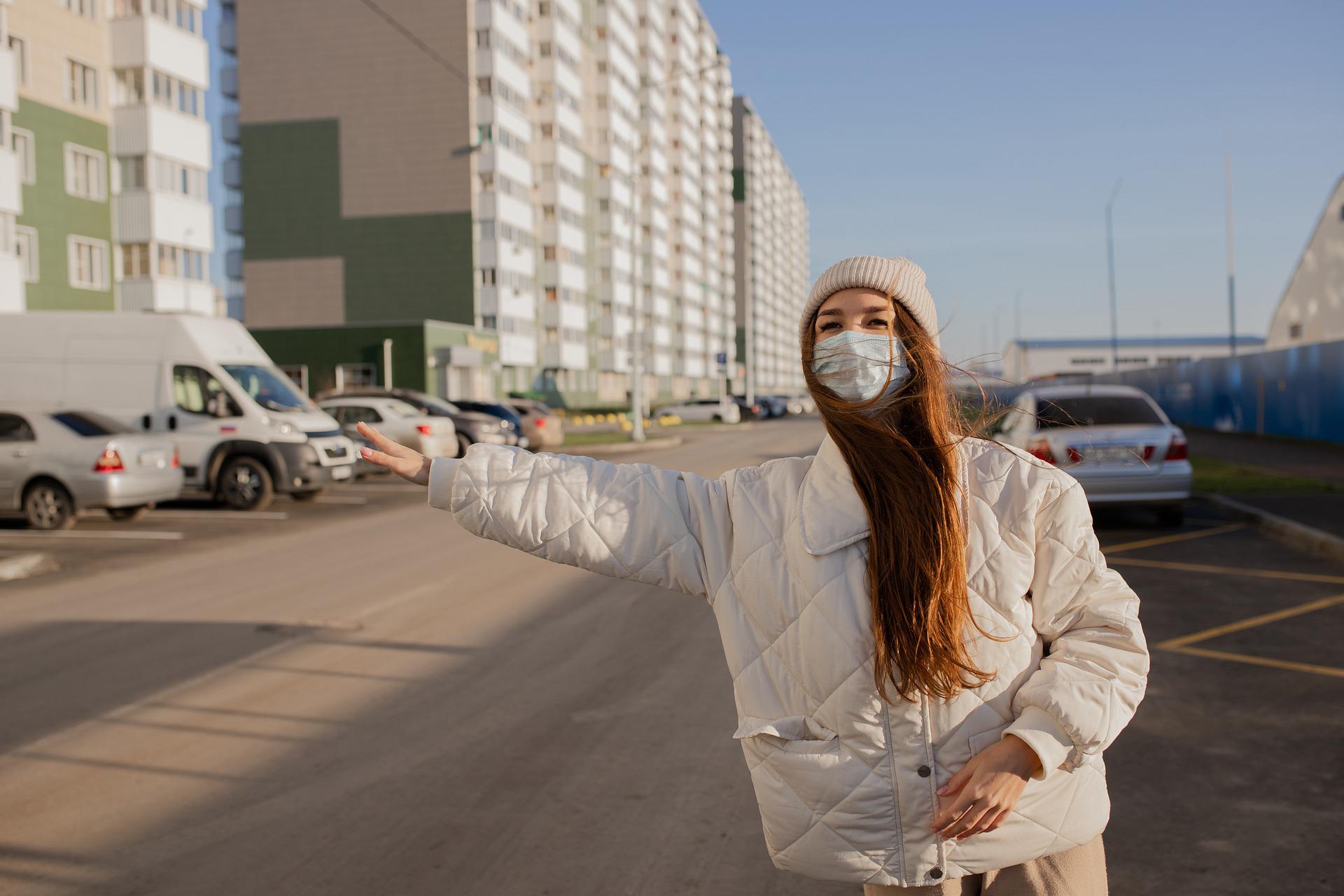 Woman wearing mask instructing cab driver, safe taxi booking, COVID safety, urban commute concept