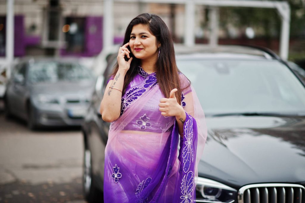 Indian girl wearing a violet traditional saree, portrait-style photo.
