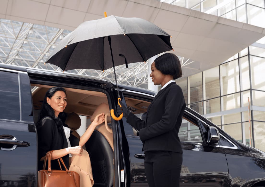 ProRido chauffeur assisting passenger with umbrella at airport in rain luxury van