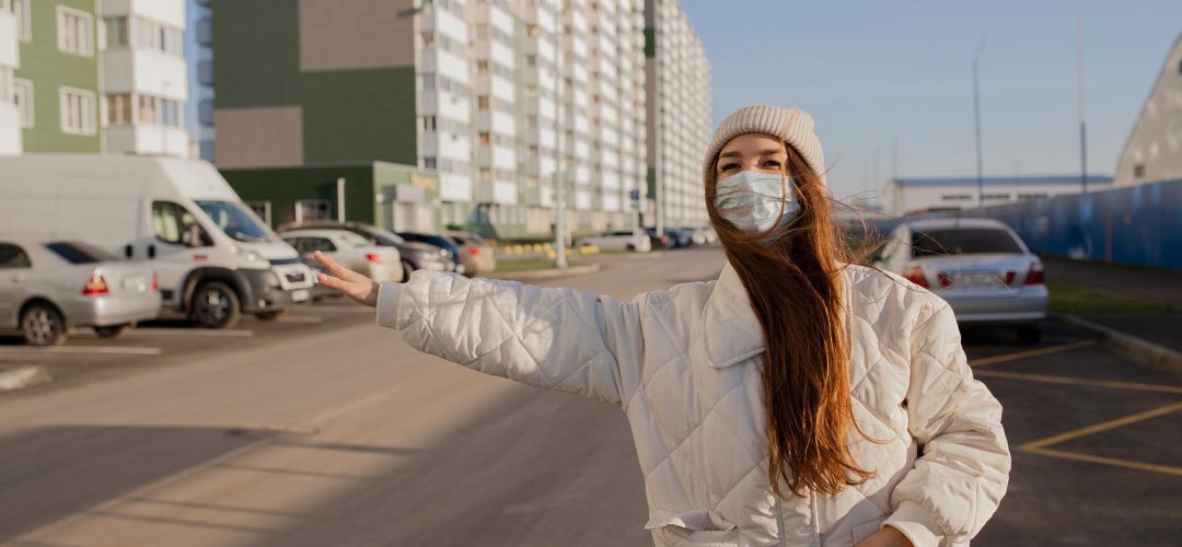 Woman wearing mask instructing cab driver, safe taxi booking, COVID safety, urban commute concept